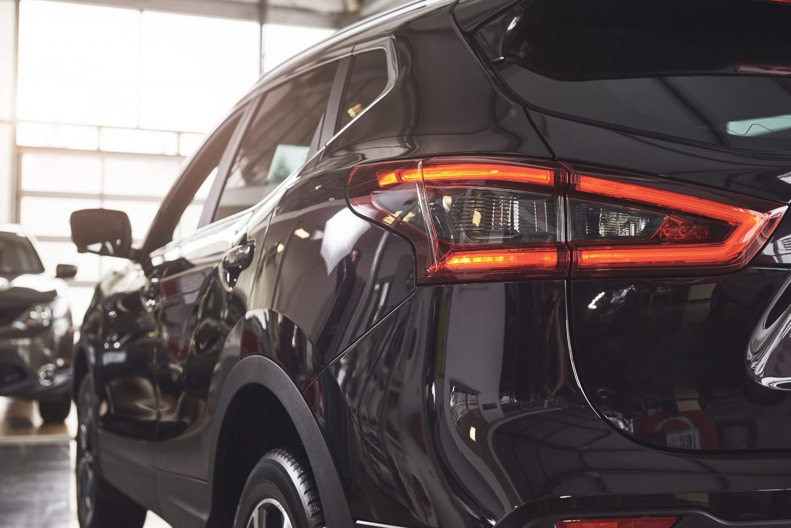 Die Rückseite eines schwarzen SUV mit leuchtenden Rücklichtern steht als automatisch gespeicherter Entwurf im Showroom