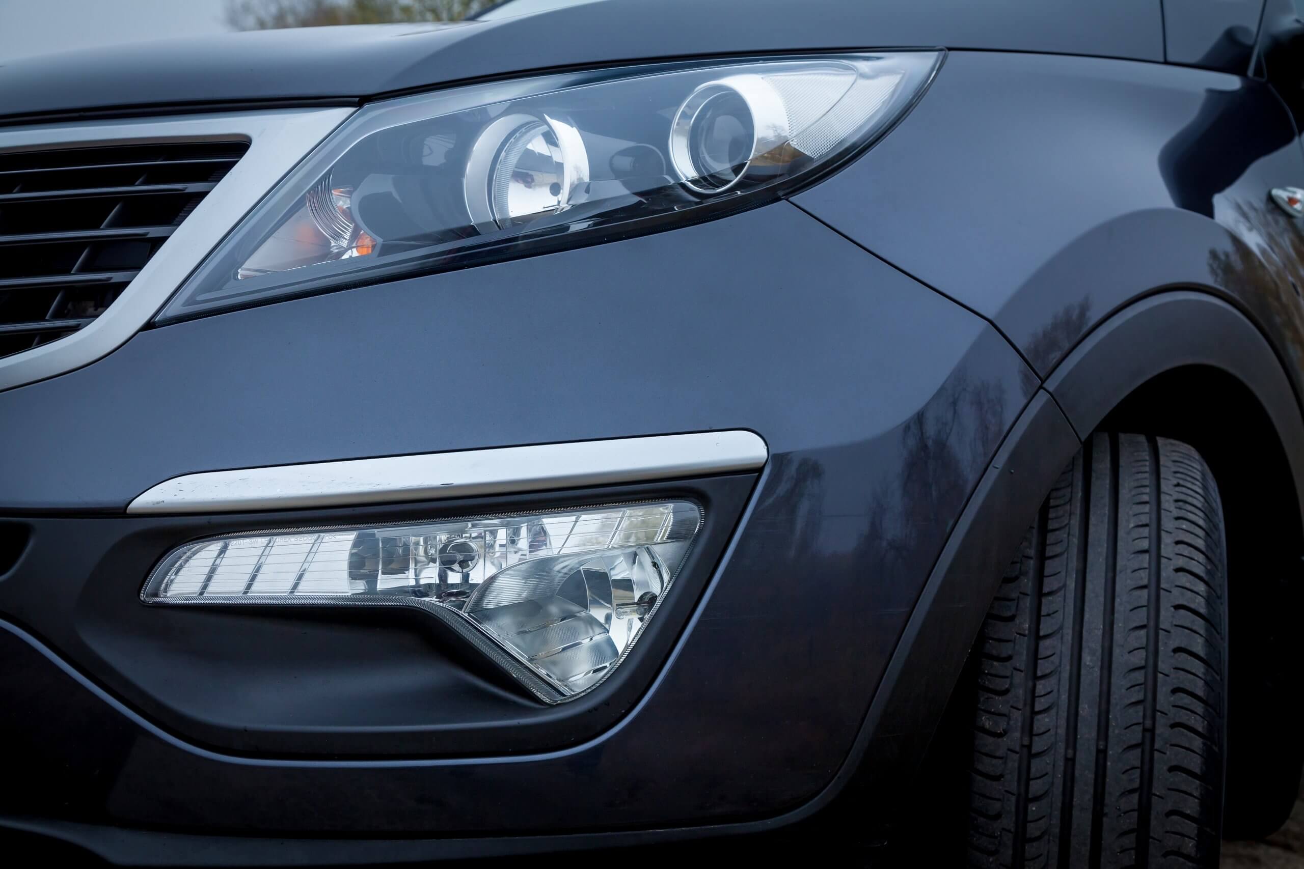 Nahaufnahme des Frontscheinwerfers und Kühlergrills eines dunkelblauen Autos mit modernem, elegantem Design-ein automatisch gespeicherter Entwurf